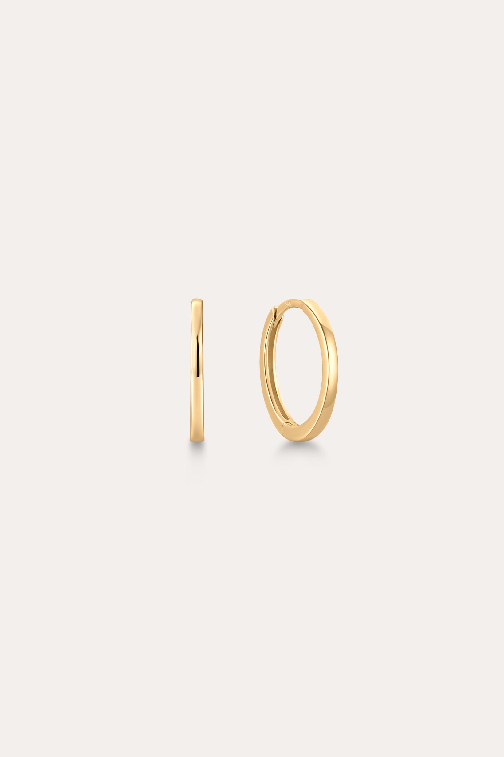 The 14K Recycled Solid Gold Plain Huggie Earring is shown on a light background, with one earring displayed from the side and the other highlighting its classic circular shape.