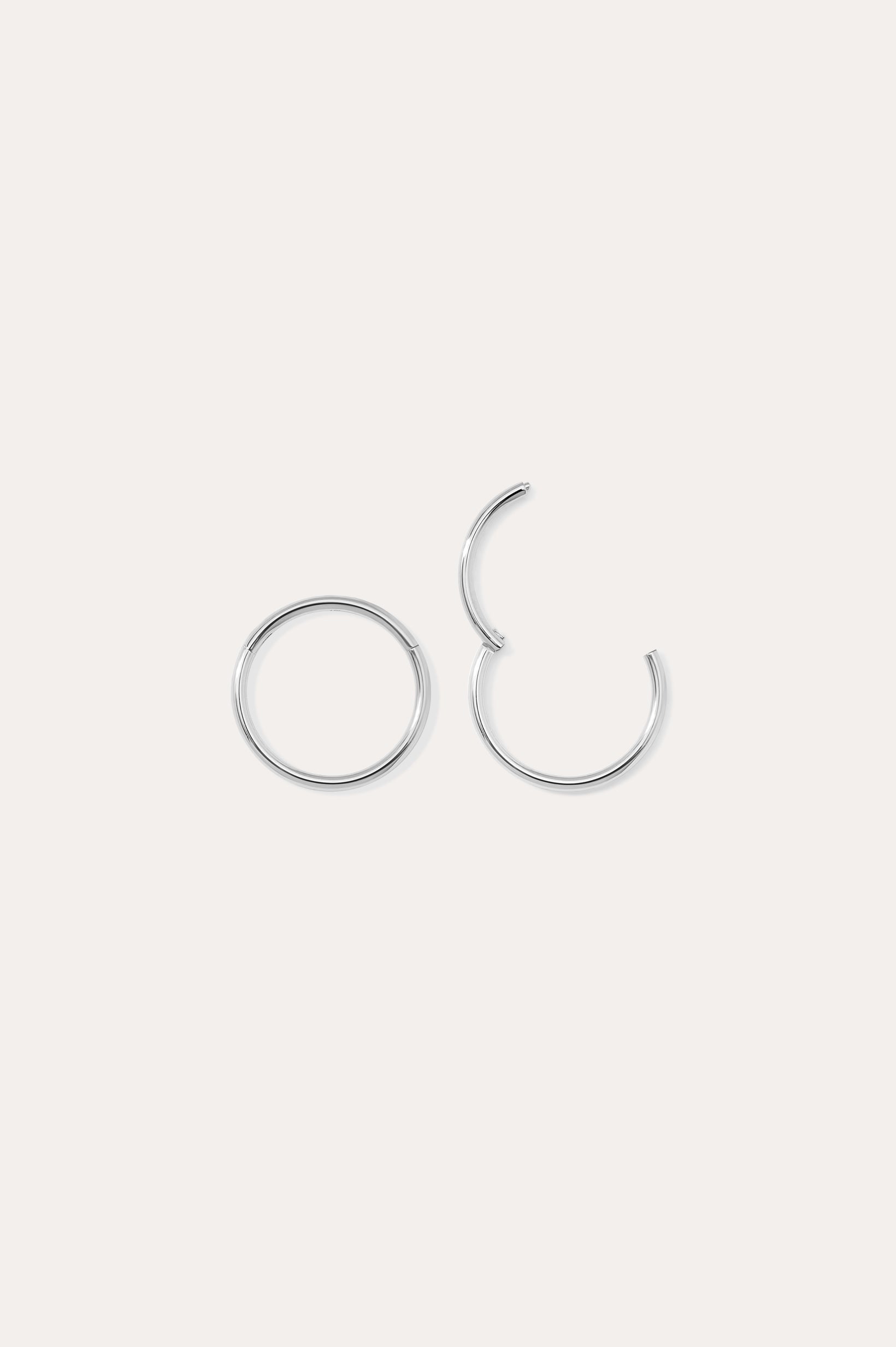 Two 14K Solid White Gold 20G Mini Clicker hoops are displayed on a plain white background—one closed, one slightly open—highlighting their simple, elegant circular design suitable for use as a nose ring or subtle ear accessory.
