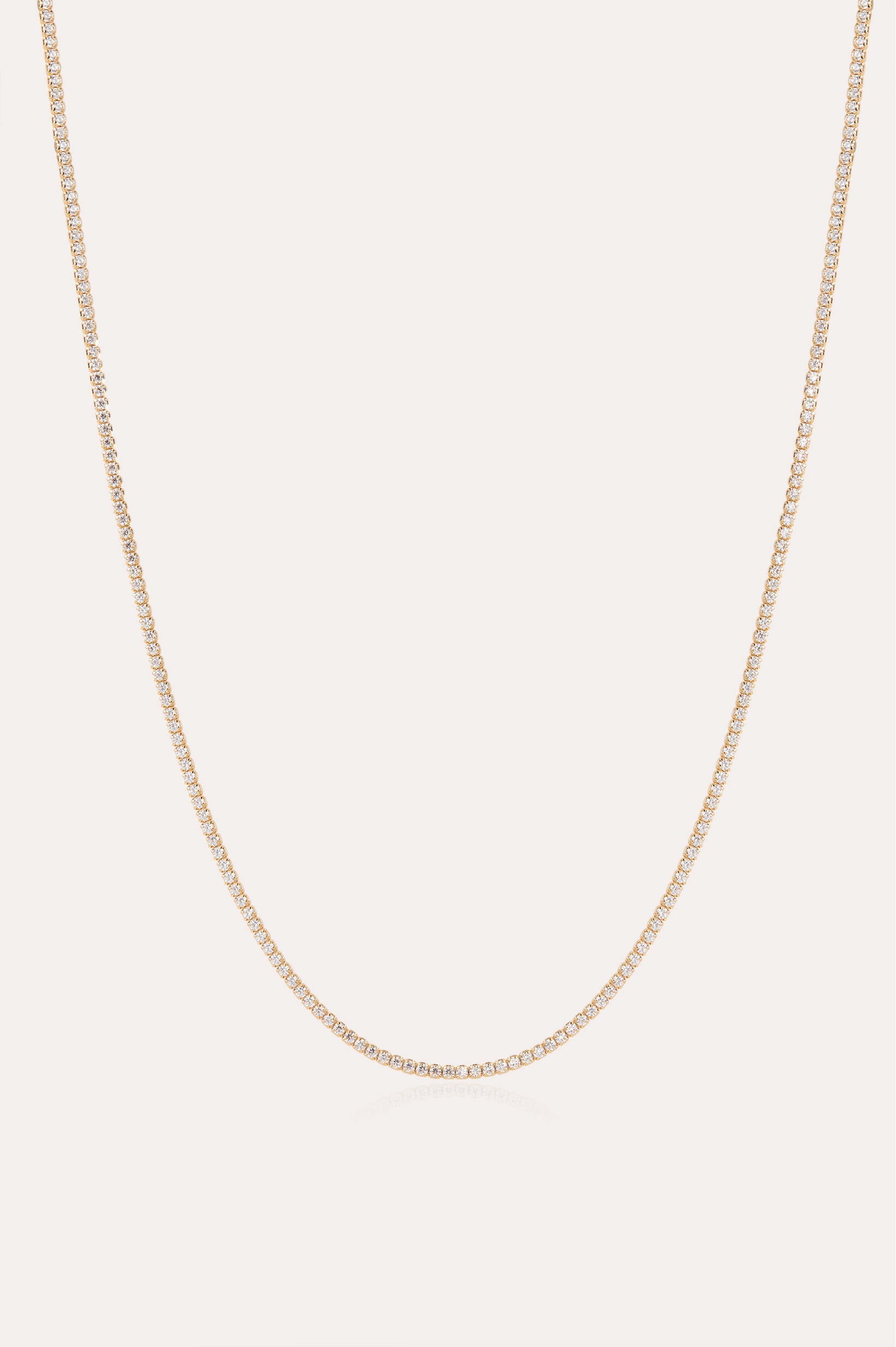 The Alba Tennis Necklace in Gold features a thin, simple design with fine links and a subtle shine, shown in a gentle curve against a light background.