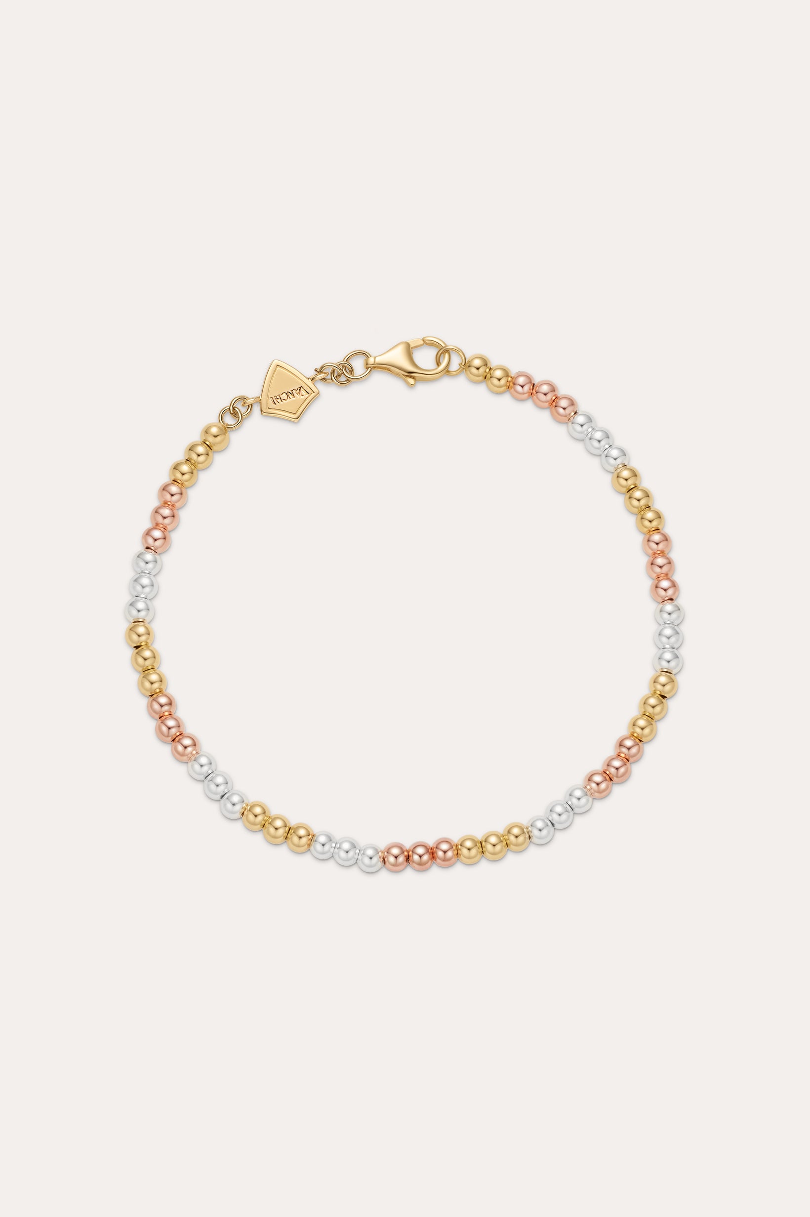 The Cecelia Three Tone Trinity Bracelet features small gold, sterling silver, and rose gold beads in a gradient pattern with a gold clasp and tag. This dainty bracelet is 18k gold plated and styled on a light background.