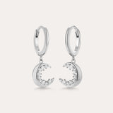 Crescent Moon Crystal Charm Huggies in Silver feature dangling crescent moon charms with sparkling cubic zirconia, shown on a light background.