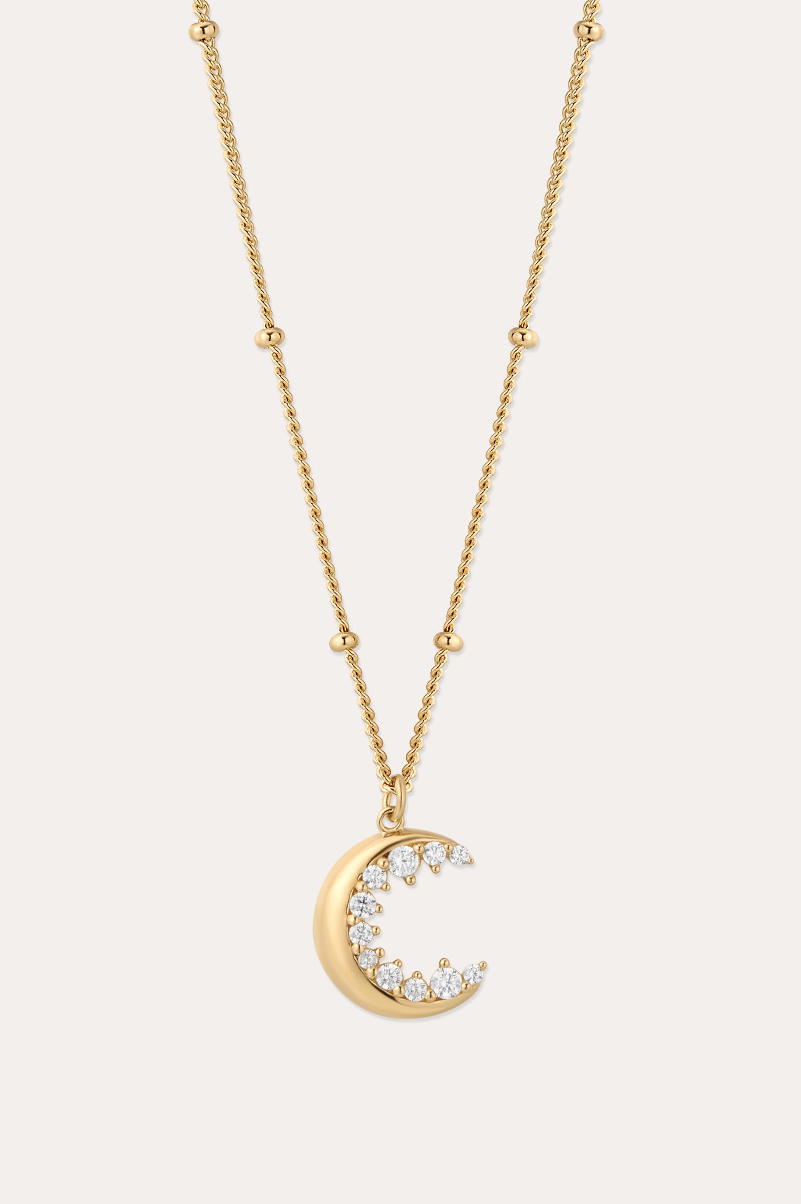 The Crescent Moon Crystal Charm Beaded Necklace in Gold features a beaded chain and a crescent moon pendant with sparkling clear stones, shown against a simple light background.
