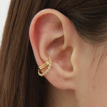 Close-up of a person’s ear with two gold ear cuffs, one smooth and one beaded. The person has straight brown hair and fair skin. Add sparkle by pairing these cuffs with the Vina Crystal Bezel Ear Cuff in Gold.