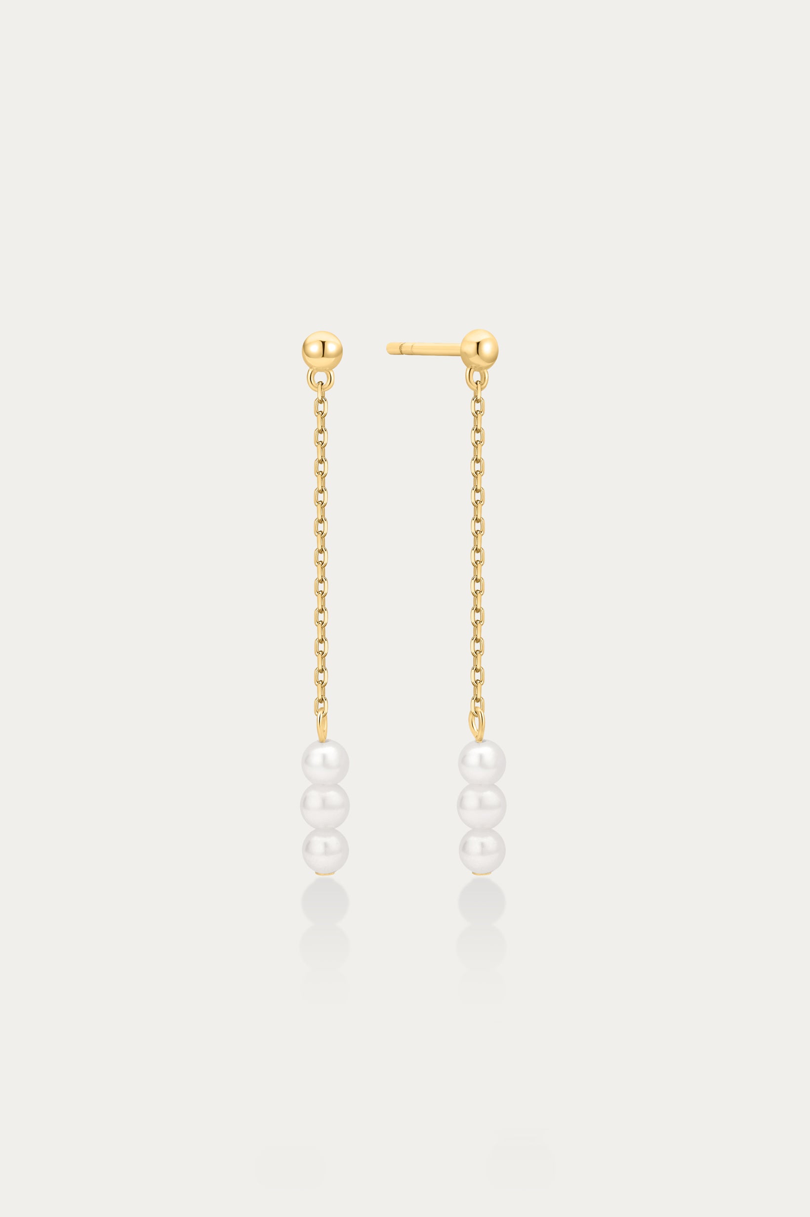 Gold chain earrings with pearls on a light gray background