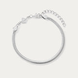 The Estelle Herringbone Chain Bracelet in Silver features a 3mm sleek chain, an adjustable extension, and a small charm by the clasp, shown against a plain white background.