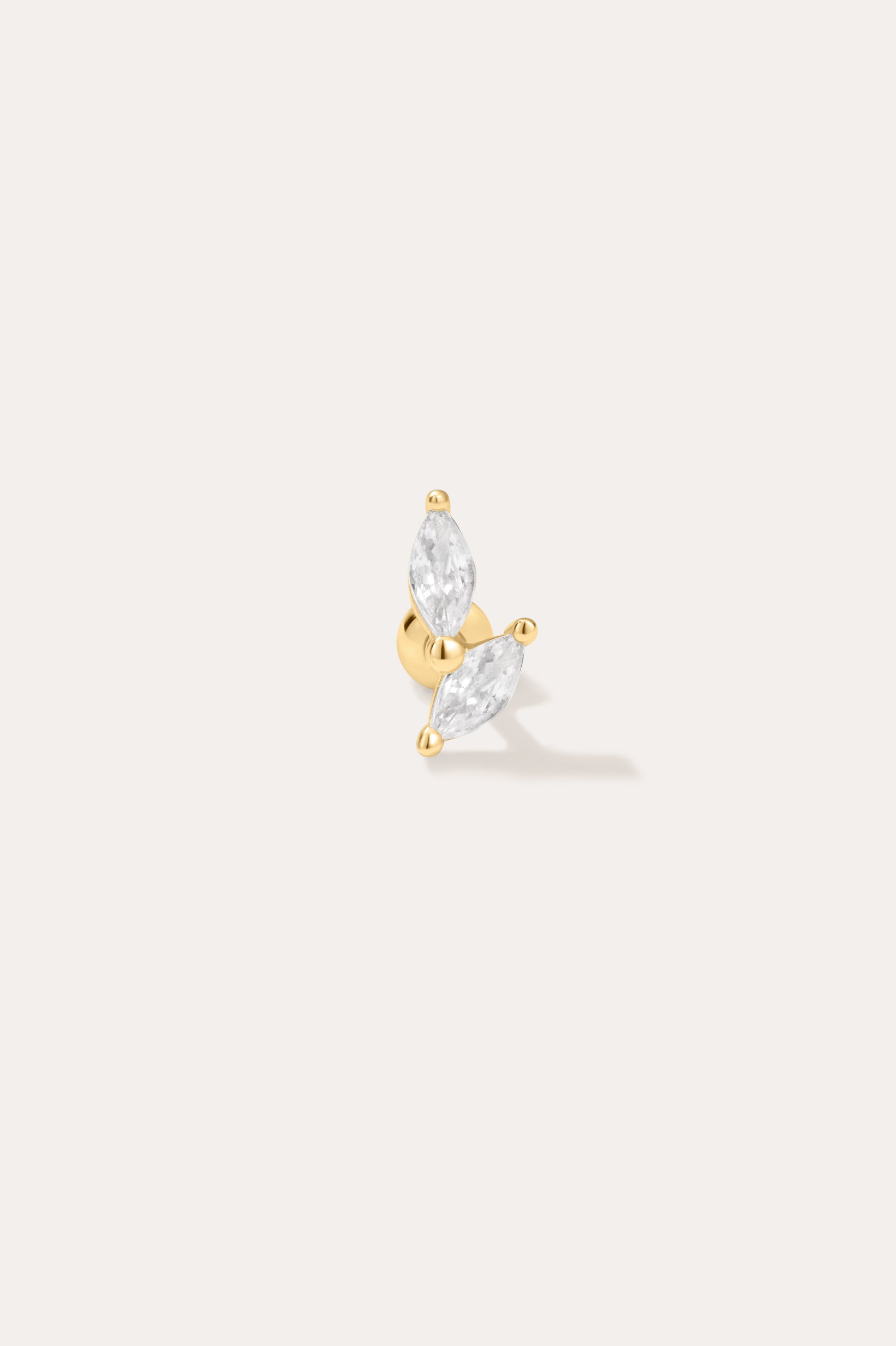 The Flora Barbell Stud in Gold showcases two marquise-cut clear gemstones set in a V shape, ideal as cubic zirconia earrings or for helix piercings, displayed against a plain off-white background.