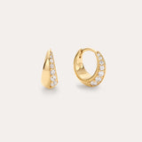 The Georgie Crystal Knife Edge Huggie Hoop Earrings in Gold feature a row of sparkling white gemstones along the front, shown against a plain light background.