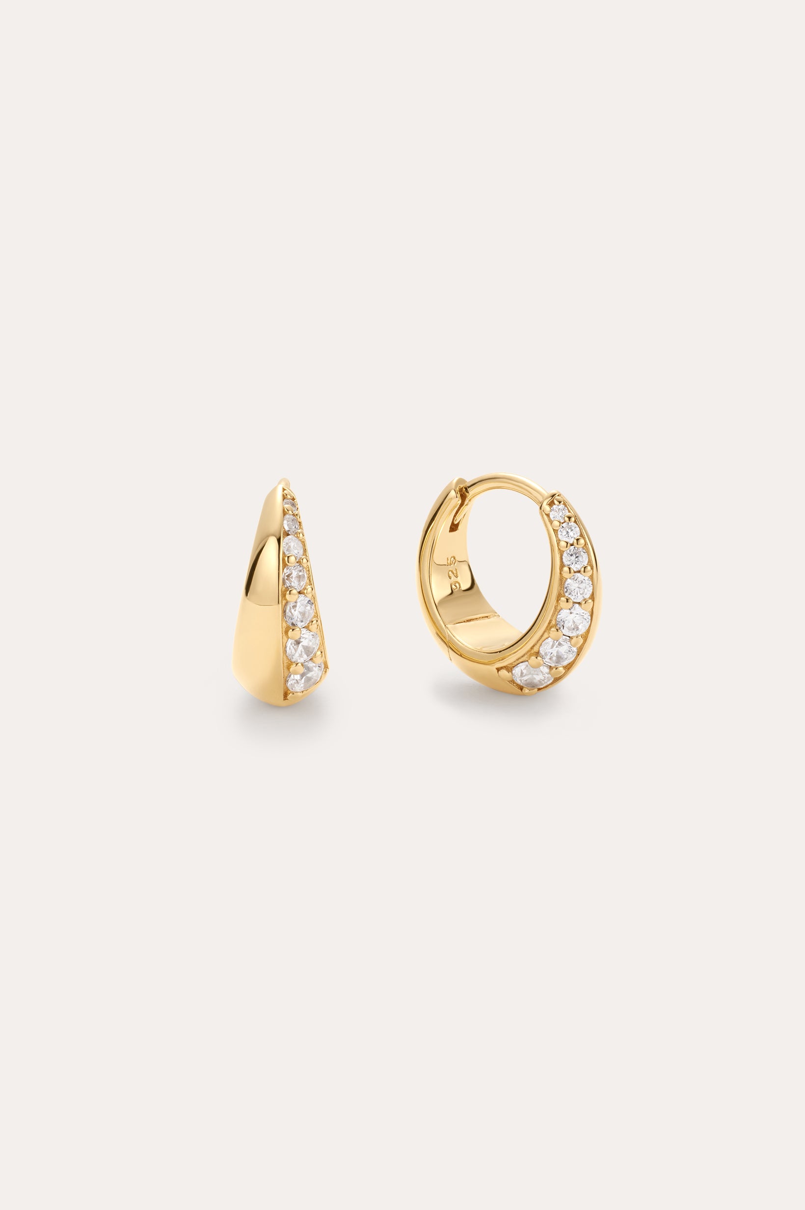 The Georgie Crystal Knife Edge Huggie Hoop Earrings in Gold feature a row of sparkling white gemstones along the front, shown against a plain light background.