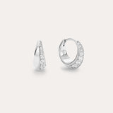 The Georgie Crystal Knife Edge Huggie Hoop Earrings in Silver feature a row of sparkling white stones, shown on a plain light background with one earring displayed from the front and the other from the side.