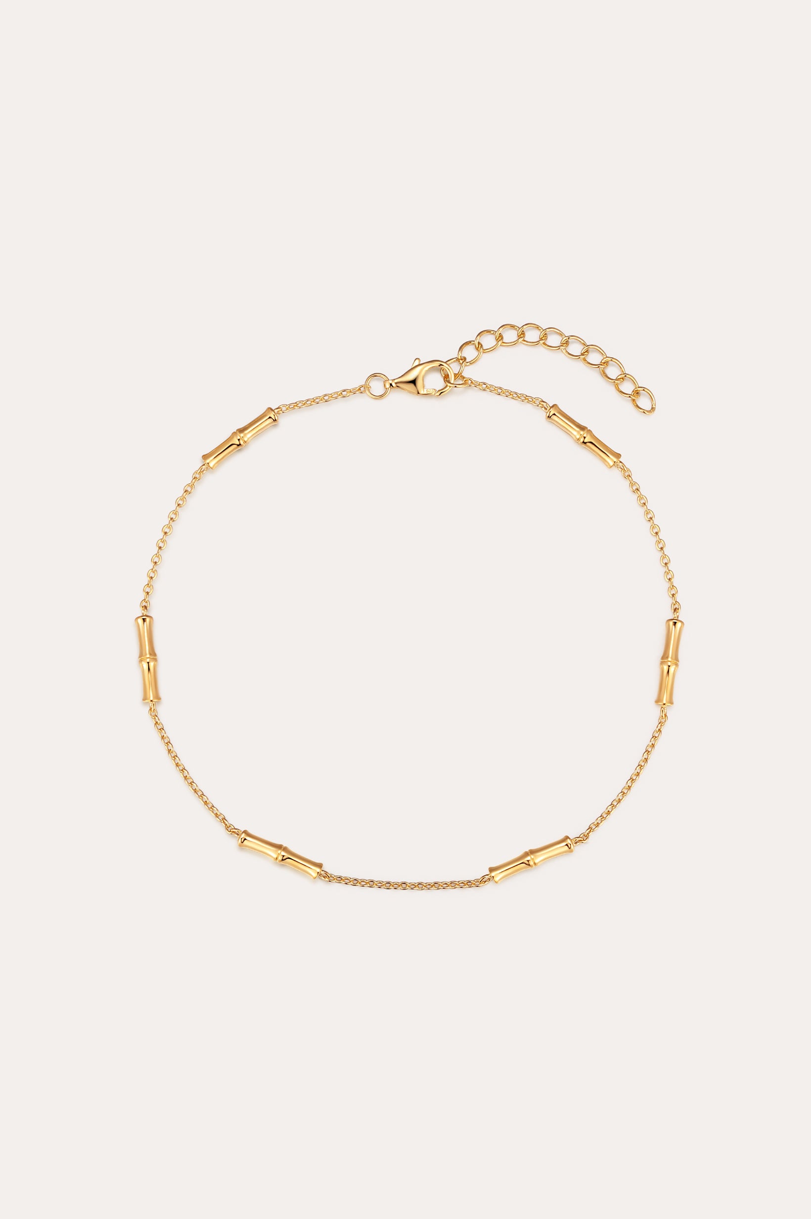 The Bamboo Chain Anklet in Gold features delicate cylindrical bar accents, crafted with 18k gold plating and an adjustable clasp with extension chain for the perfect fit.
