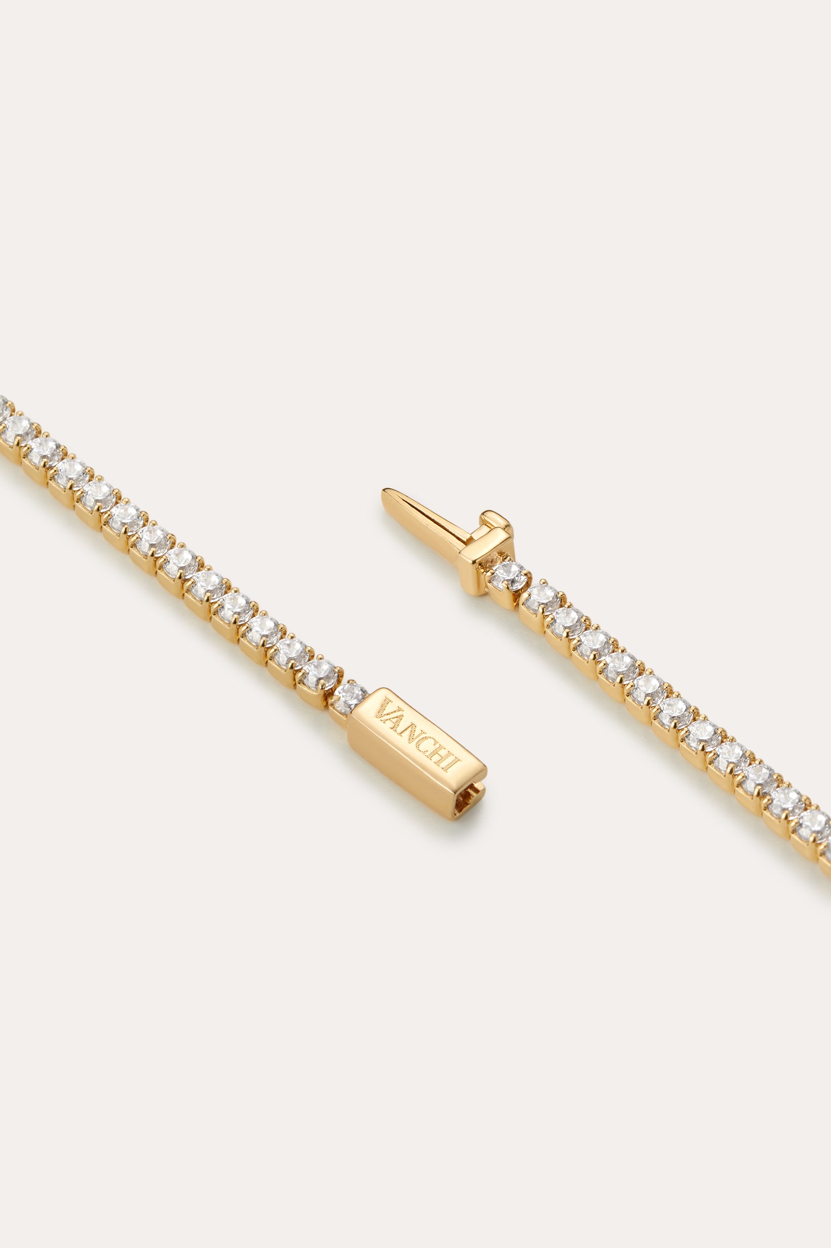 A close-up of the Lumi Tennis Bracelet in Gold shows small round white stones and a rectangular clasp engraved with VANCLI.