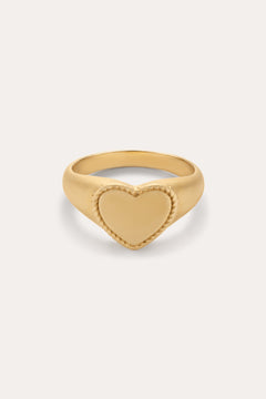 The Willa Heart Pinky Signet Ring in Gold is crafted in 18k gold with a flat heart-shaped centerpiece and a textured, rope-like border, shown against a plain light background.