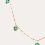 The Thea Green Heart Pendant Gold Necklace is a delicate adjustable gold chain adorned with five evenly spaced, small green cubic zirconia heart-shaped gemstones.