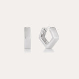 The Judith Hexagon Angular Huggies in Silver, featuring a chunky geometric design, are shown on a plain light background—one upright and one open to reveal the clasp. Perfect for stacking earring looks.