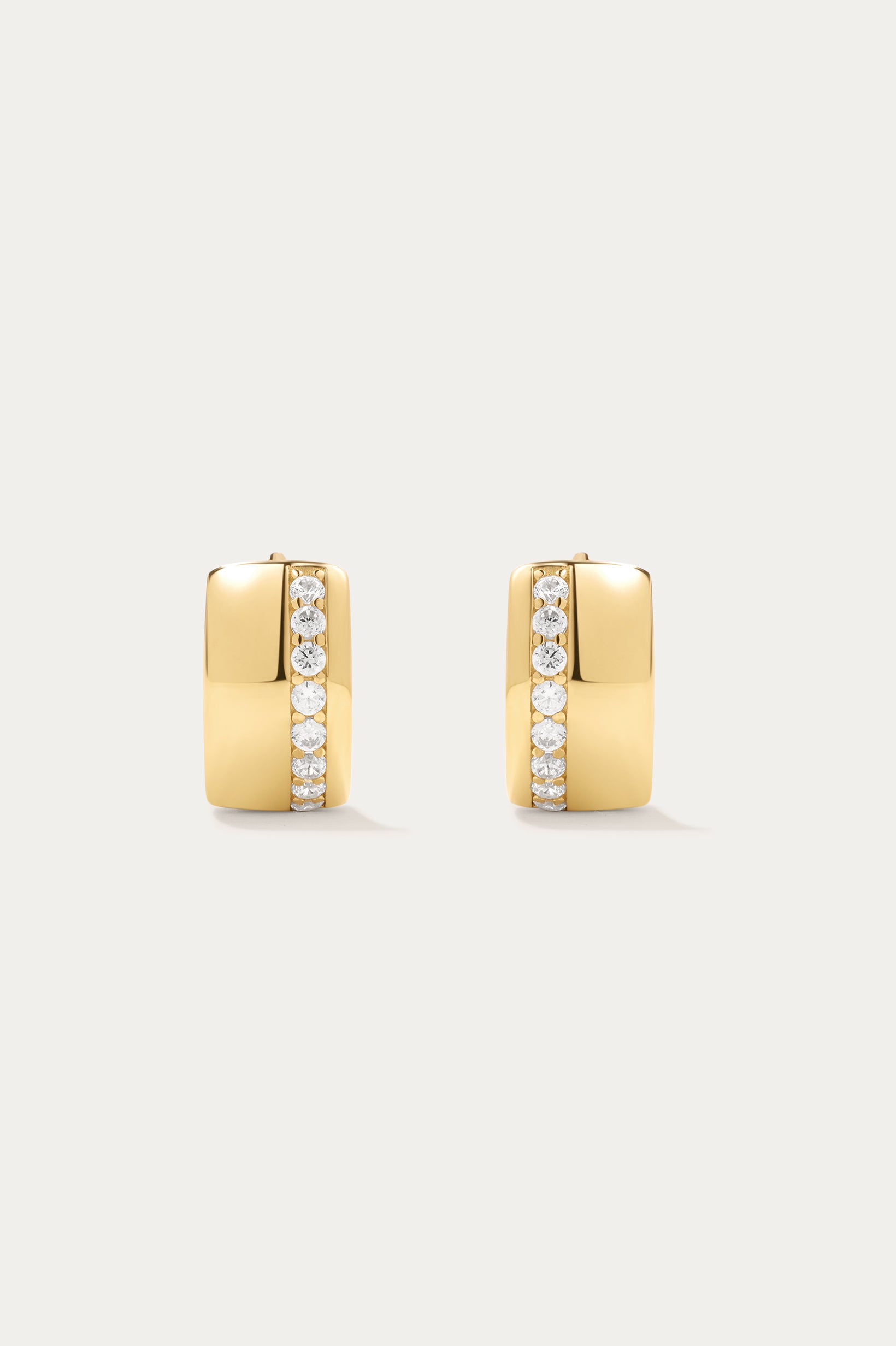 The Juni Pavé Chunky Hoop Earrings in Gold feature a modern rectangular shape, 18k gold plating, and a vertical row of sparkling CZ crystals on each polished huggie hoop.