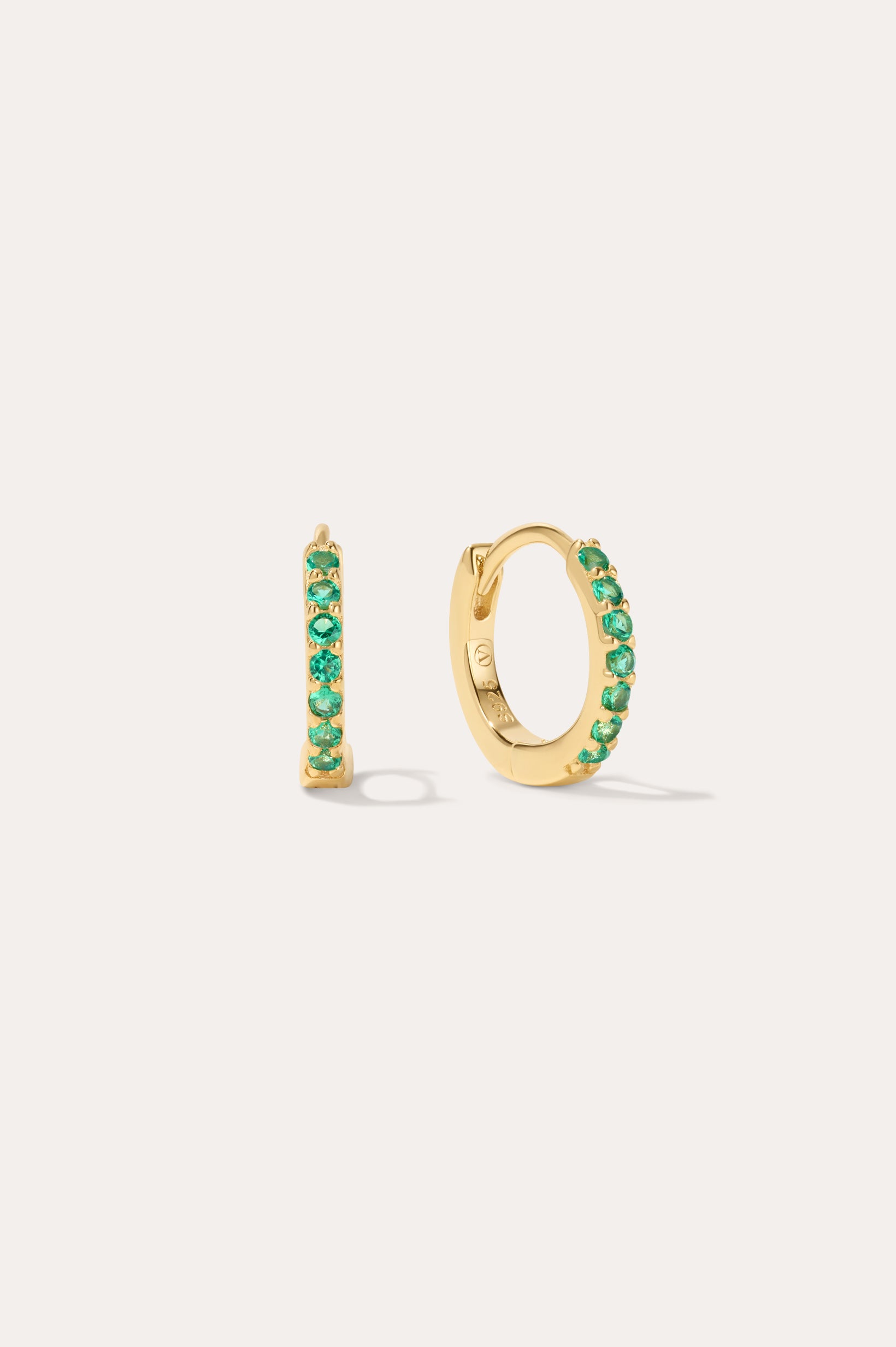 The Kiki Crystal Huggie Earrings in 18k Gold Plated/Green feature a row of green crystals on each earring, with one shown from the side and one from the front—versatile, stylish options for daily wear.