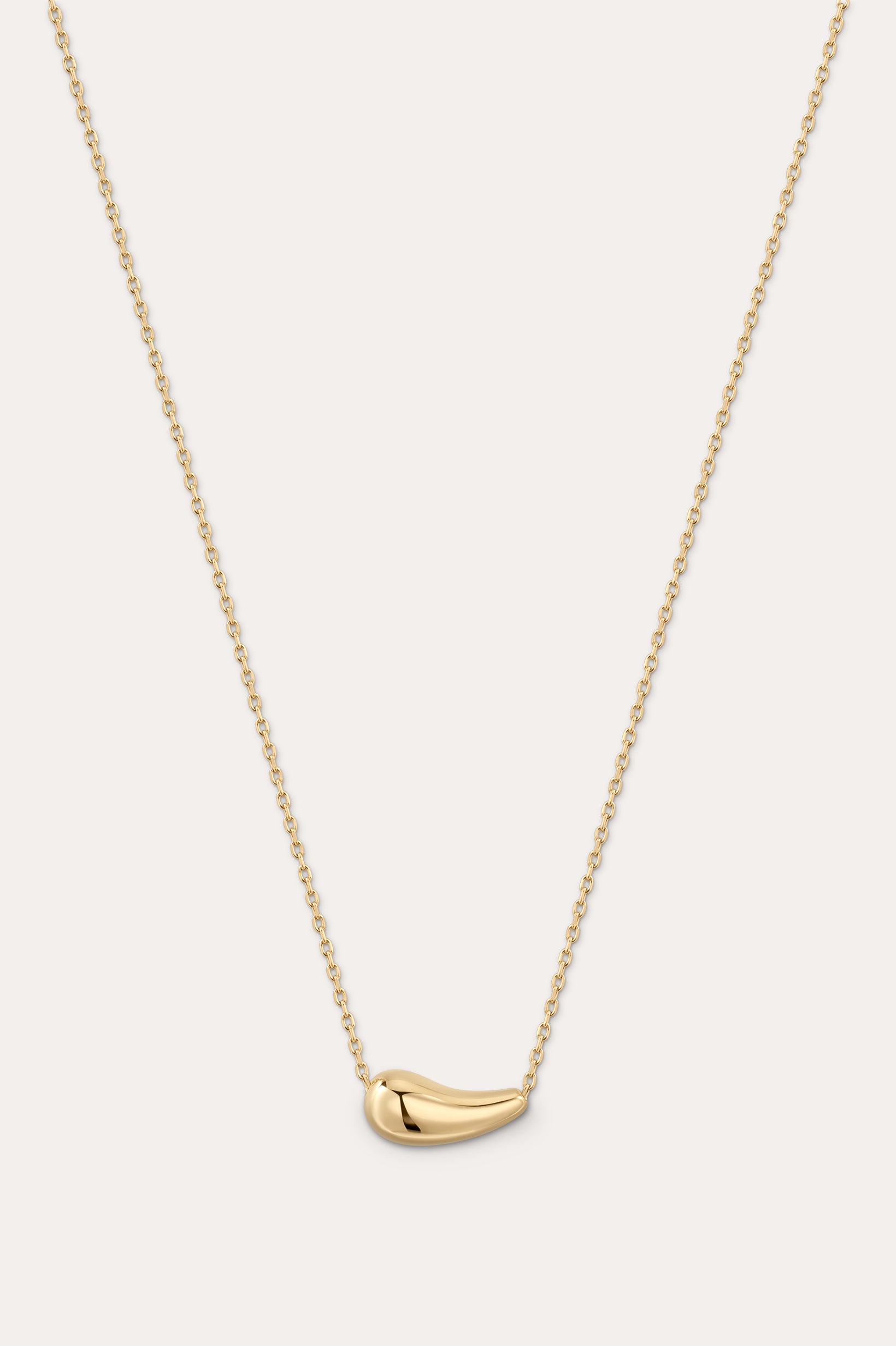 Gold necklace with a small pendant on a light gray background