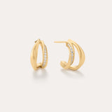 Nadine Pavé Twisted Stud Earrings in Gold feature a modern, sculptural design with a row of sparkling gemstones set along the inner edge and are displayed against a light neutral background.