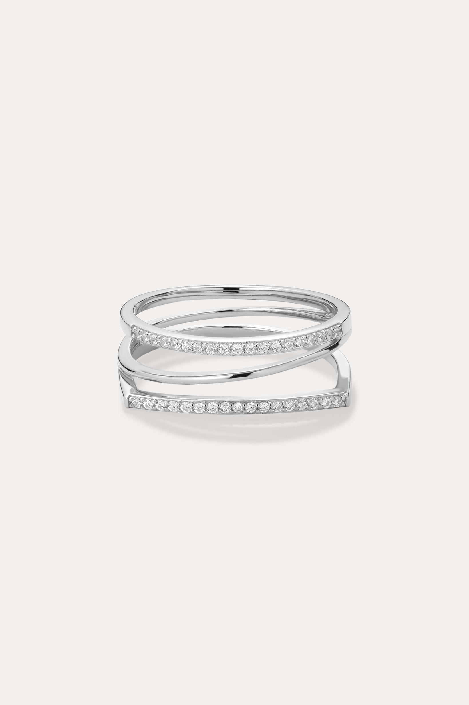 The Nola Pavé Triple Band Ring in Silver features three thin, parallel pavé bands set with sparkling white stones, connected at the sides and displayed on a plain light background.