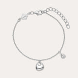 The Nora Double Pendant Bracelet in Silver features a polished heart charm at the center and a small teardrop pendant, both accented with cubic zirconia, plus an adjustable clasp and logo tag near the fastening.