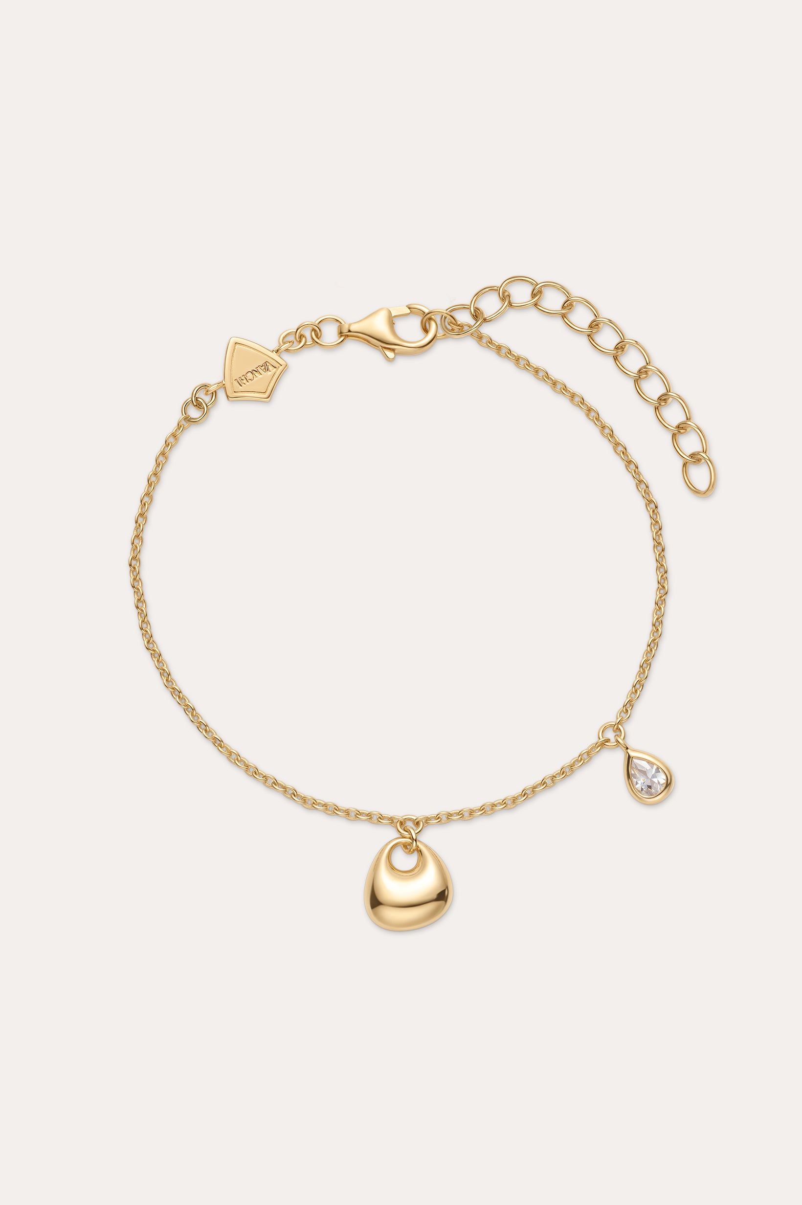 The Nora Double Pendant Bracelet in Gold features an adjustable clasp, a gold heart charm, and a teardrop-shaped cubic zirconia pendant for subtle sparkle.
