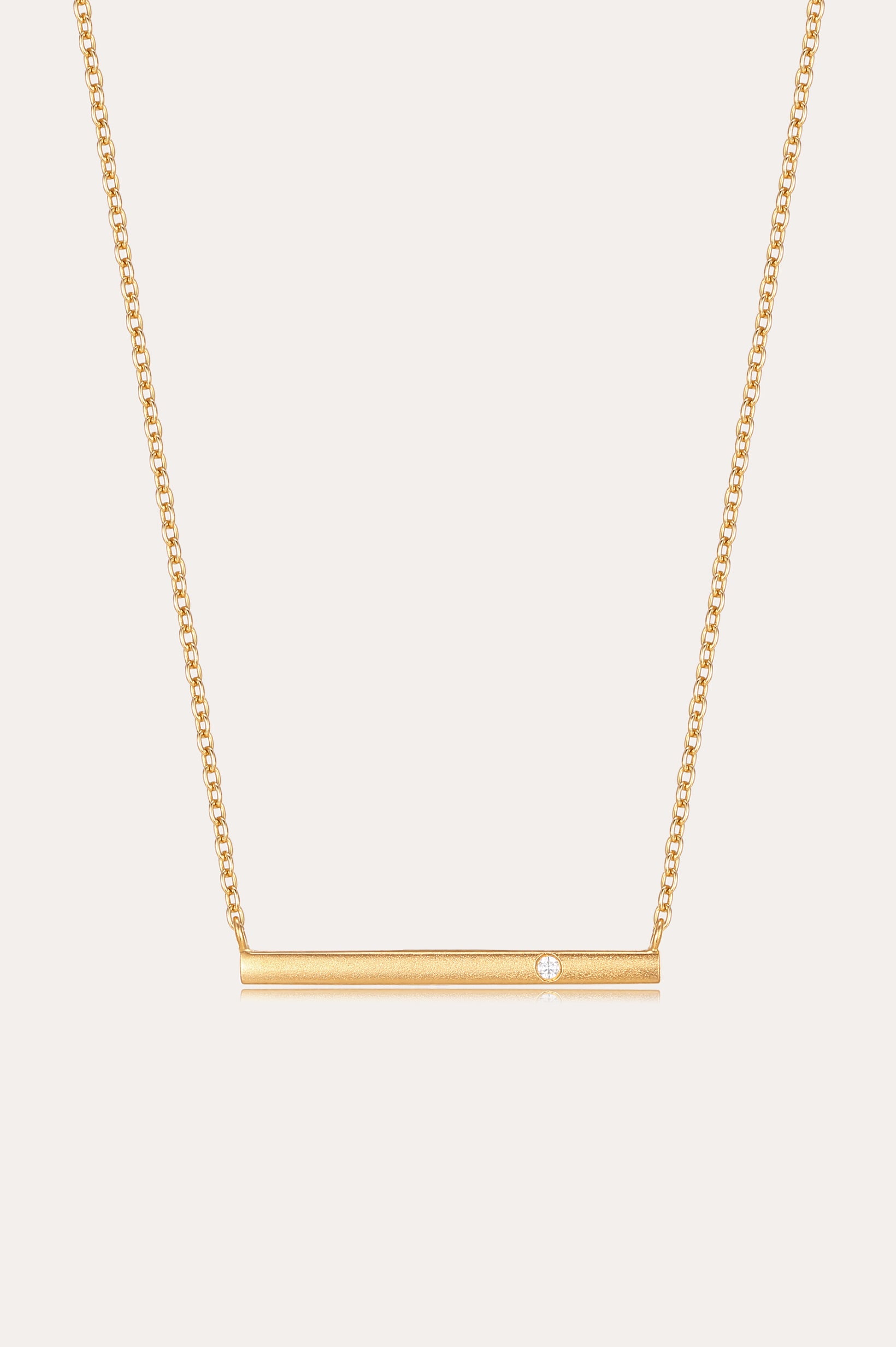 The Regina Horizontal Bar Pendant Necklace in Gold features a minimalist horizontal bar with an off-center cubic zirconia, making it perfect for lovers of simple, elegant jewelry.