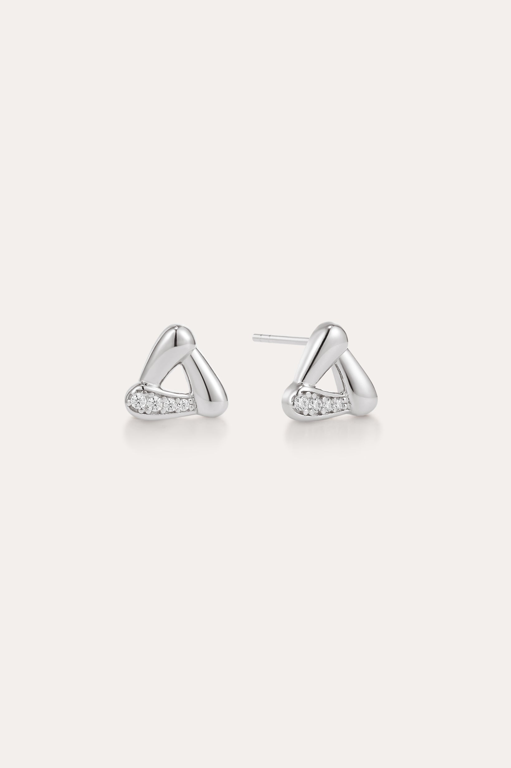 A pair of Colette Droop Link Studs in Silver, with smooth, rounded triangular shapes and small embedded cubic zirconia crystals on one side, displayed on a plain light background.