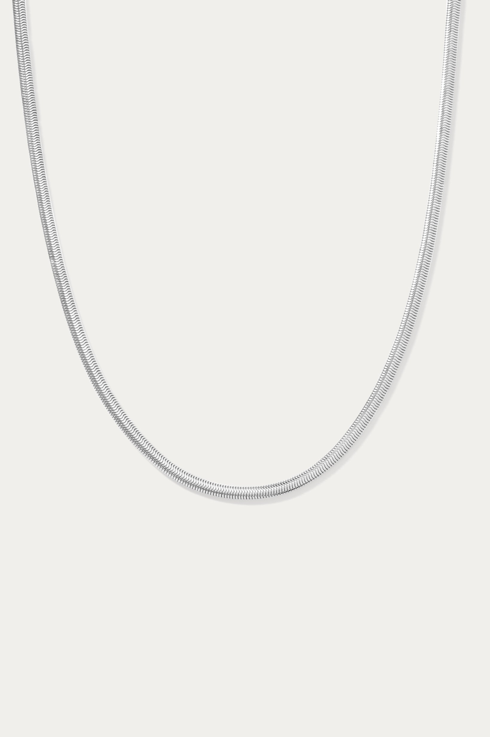 The Estelle Herringbone Chain Necklace in Silver is a sleek, minimalist chain shown against a plain white background.