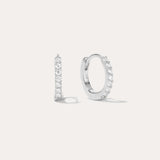 The Kiki Crystal Huggie Earrings in Sterling Silver feature a sparkling row of white gemstones. Shown facing forward and from the side, they are versatile everyday essentials for any ear piercing.