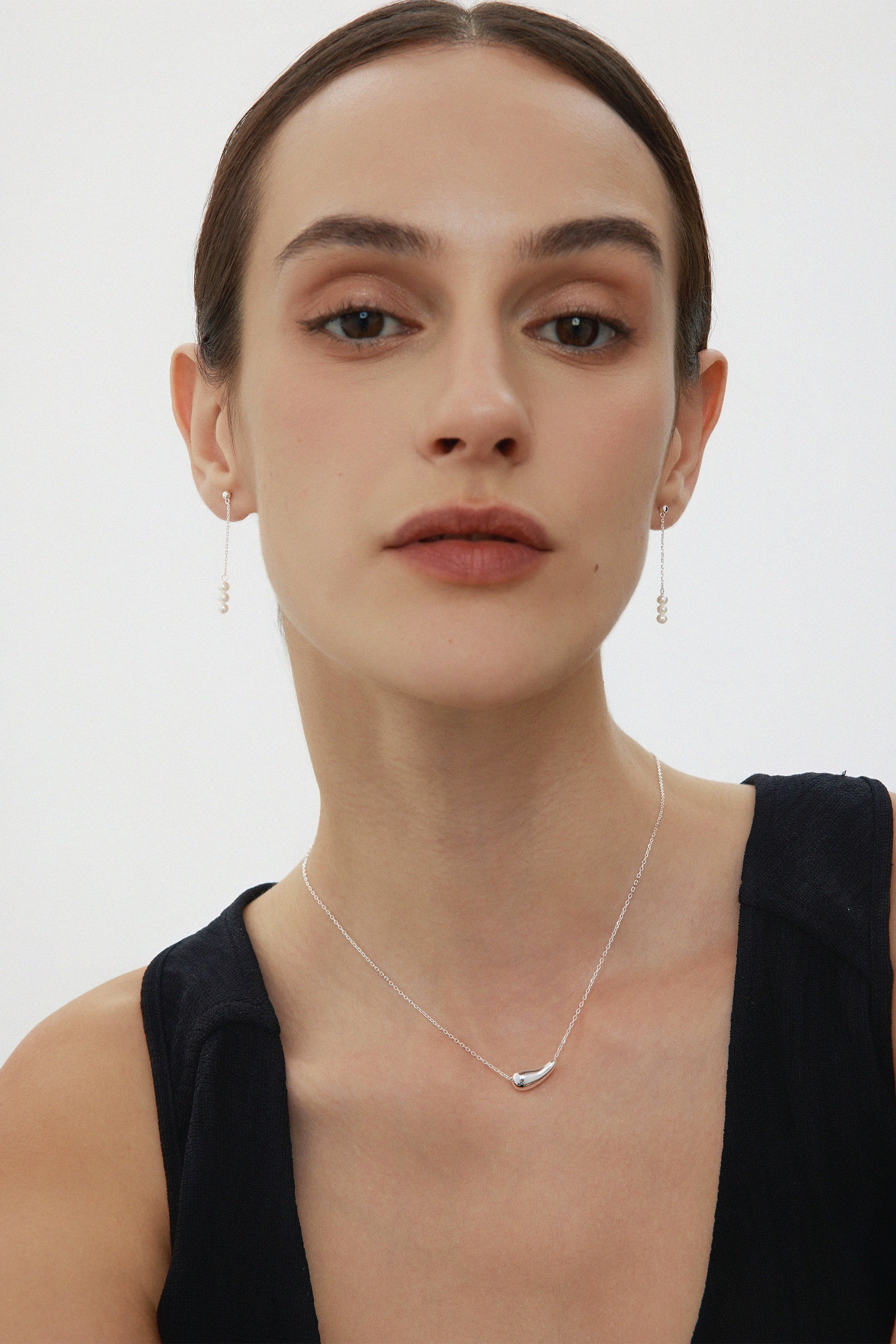 Woman wearing a delicate necklace with a plain background