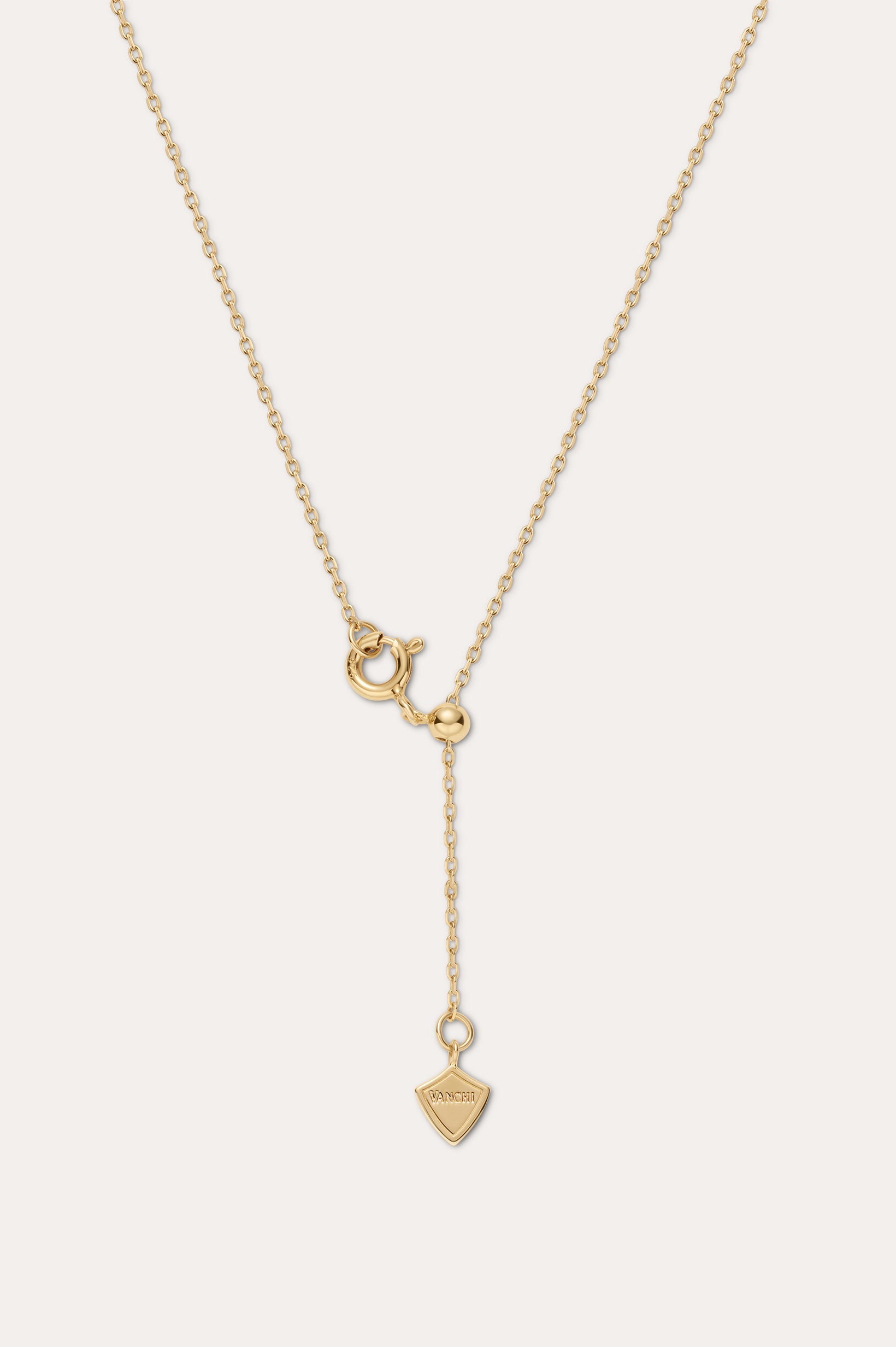 Gold necklace with a unique pendant on a light beige background