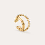 The Vina Crystal Bezel Ear Cuff in Gold features a beaded design with small, round clear cubic zirconia along the outer edge, shown on a light beige background.