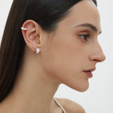 A woman with straight dark hair and a white top is shown in profile, wearing the Flora Barbell Stud in Gold adorned with marquise cubic zirconia on her upper ear and a textured silver hoop on her lobe, set against a plain light background.
