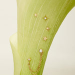 Gold star-shaped earrings with chains on a green fabric background