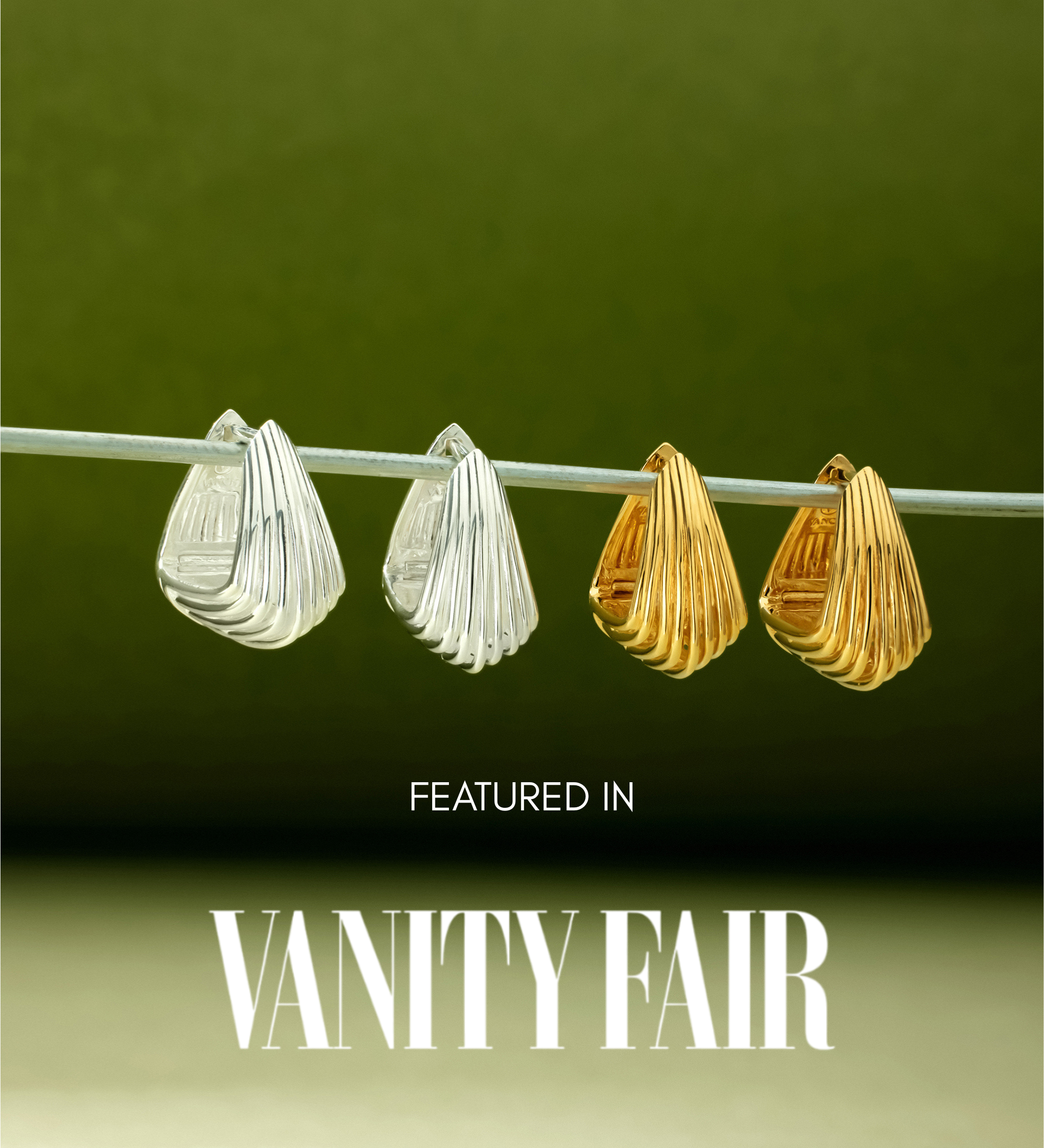 A pair of Juno Ridged Chunky Hoops in Silver hangs on a clear rod against a green gradient background. Text below reads, Featured in Vanity Fair.