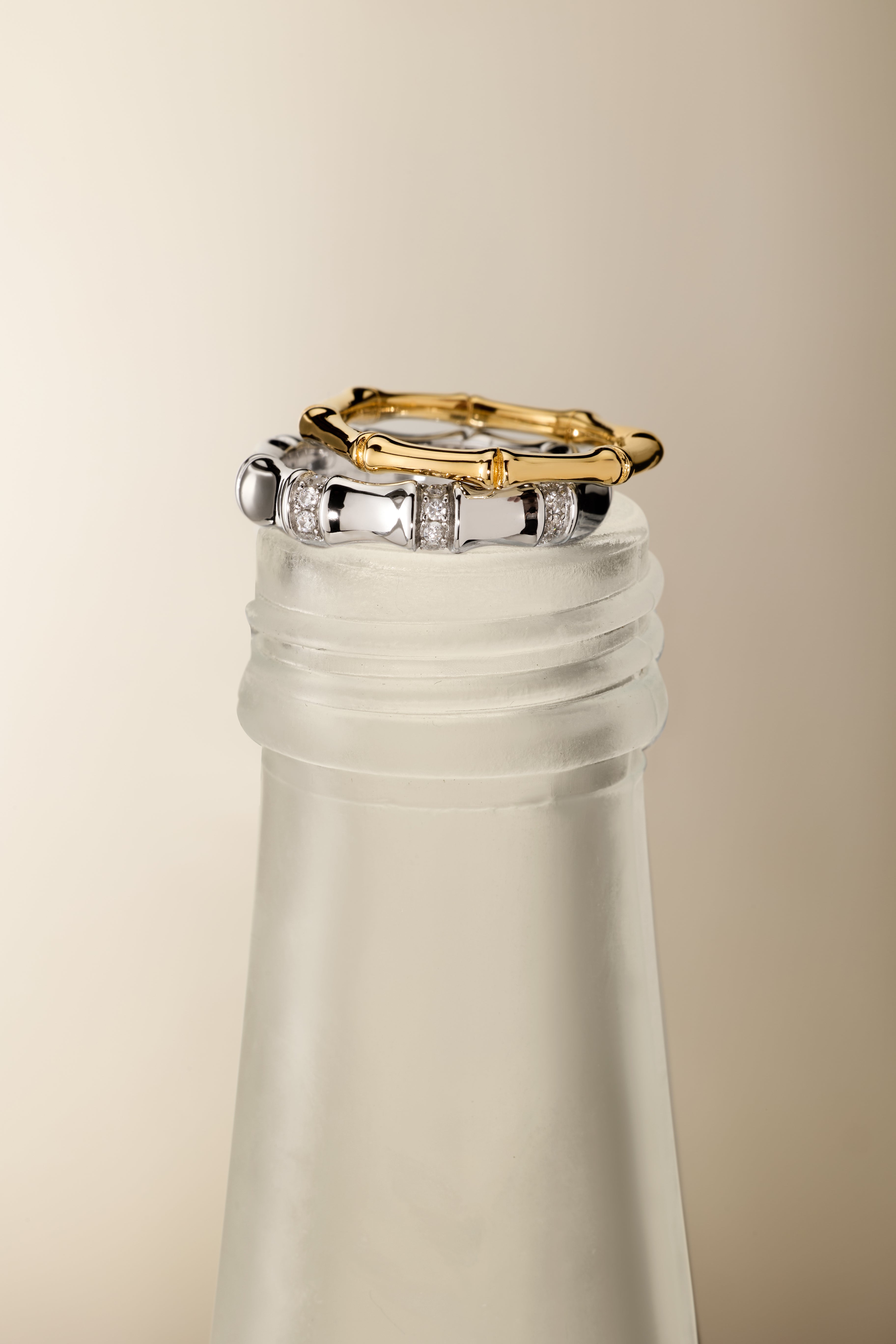 The Bamboo Chunky Crystal Ring in Silver is displayed stacked on the frosted neck of a glass bottle, set against a neutral beige background.