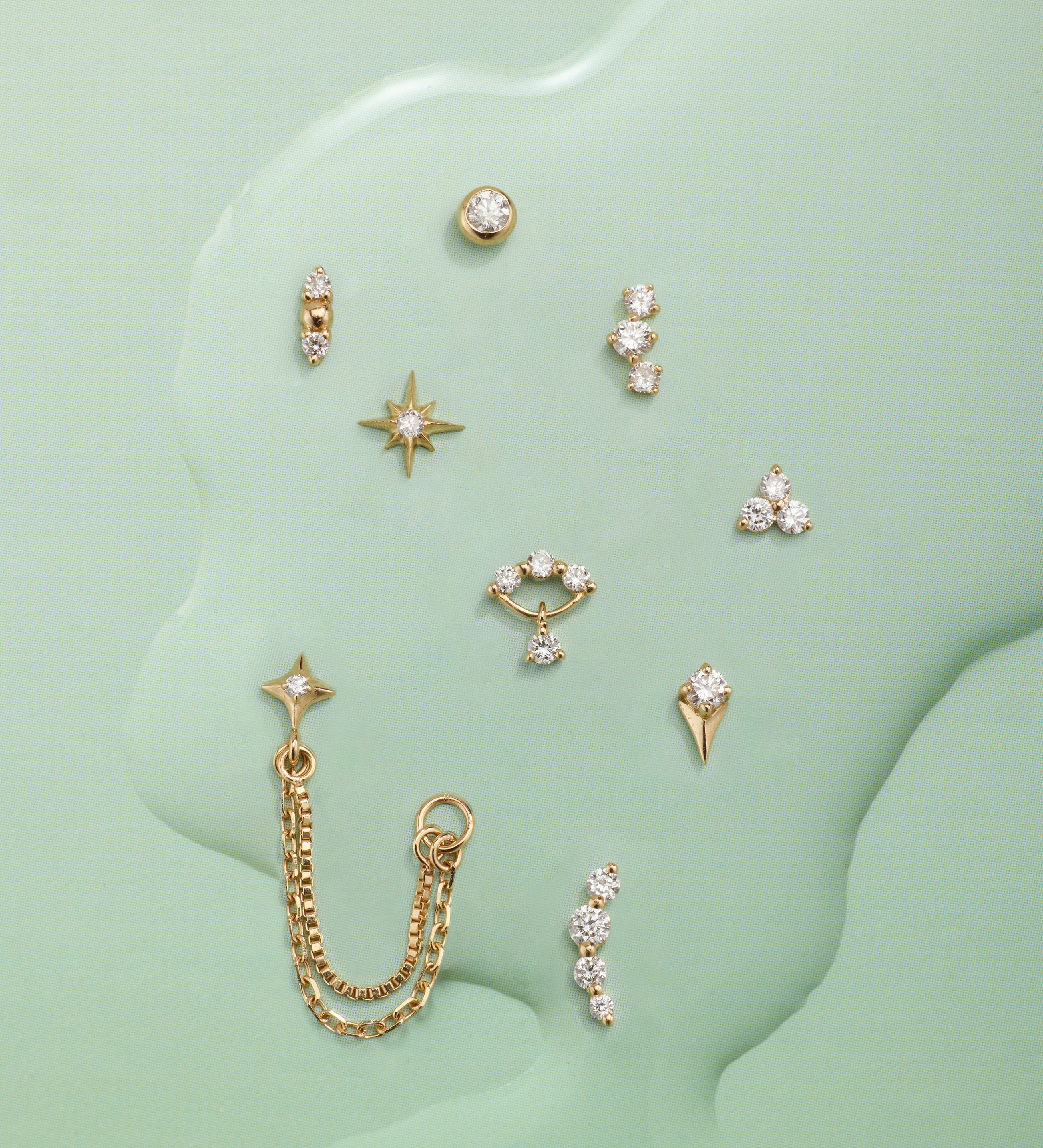 Collection of gold earrings on a green textured background