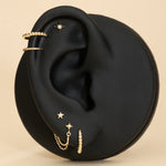 Gold earrings displayed on a black ear with a beige background