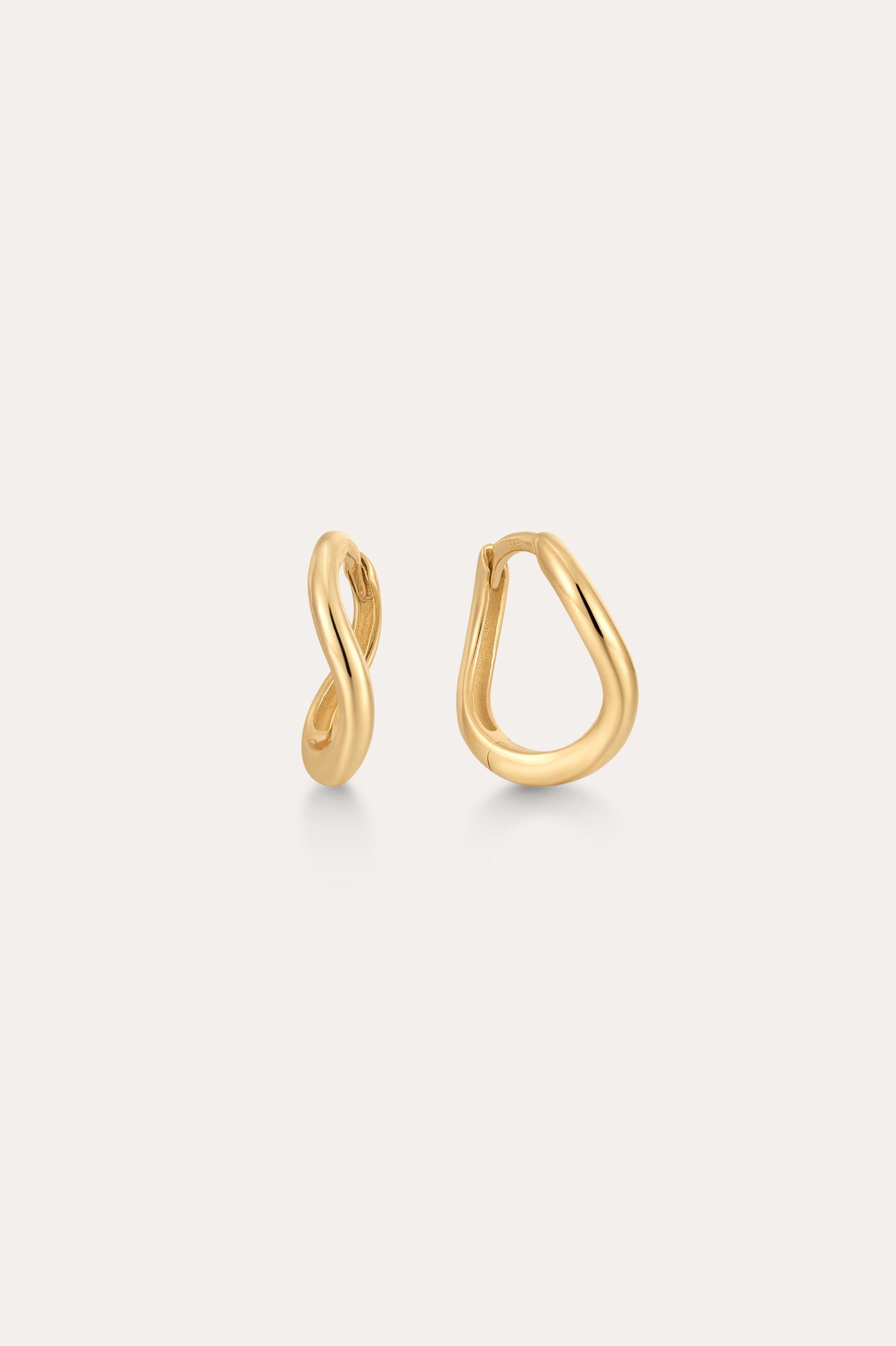 The 14K Recycled Solid Gold Twisted Huggie Earrings feature smooth, wavy, organic shapes and an asymmetrical design. These mini hoops are crafted from recycled gold and displayed on a plain light background.