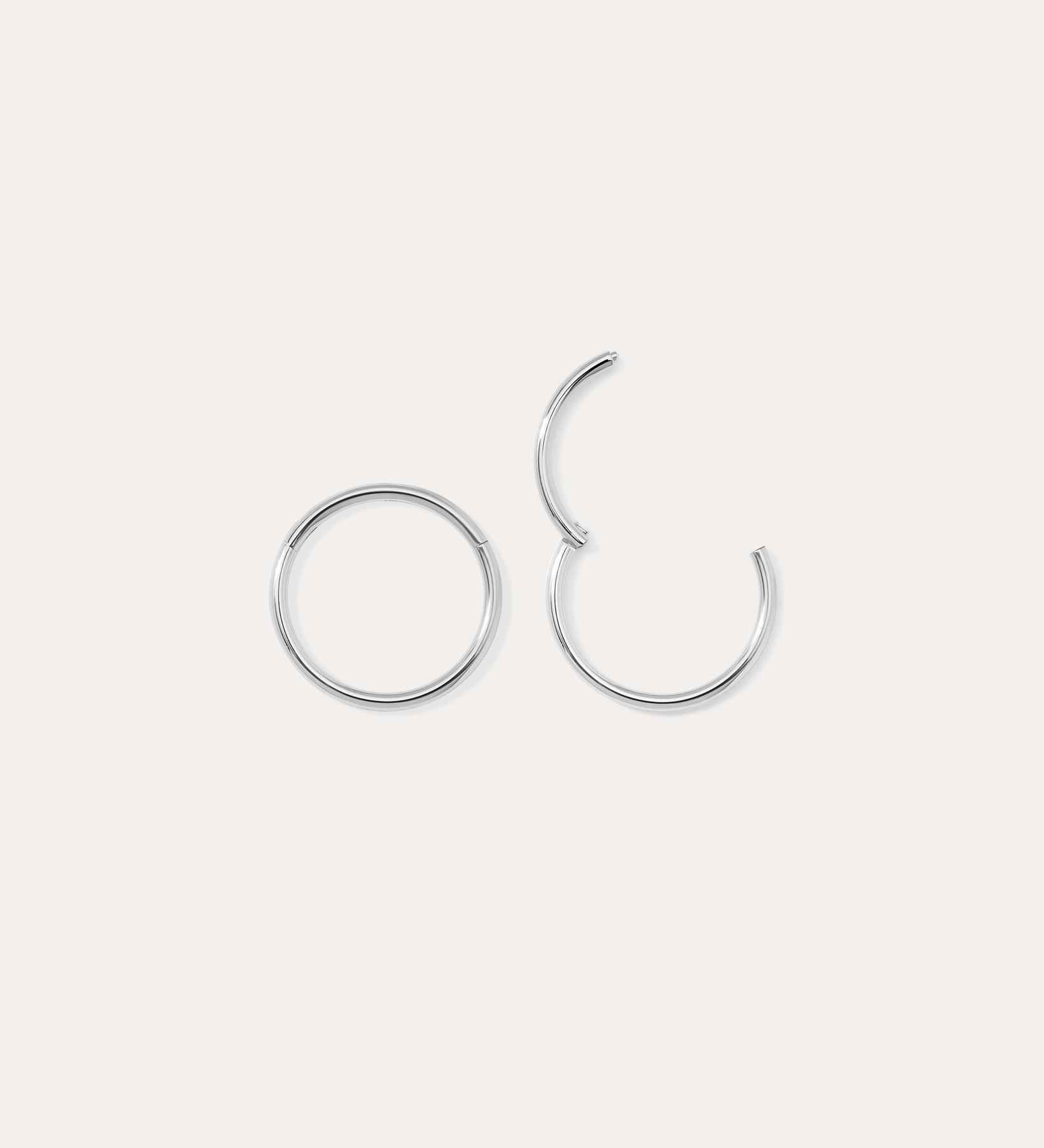 Two 14K Solid White Gold 20G Mini Clicker hoops are displayed on a plain white background—one closed, one slightly open—highlighting their simple, elegant circular design suitable for use as a nose ring or subtle ear accessory.