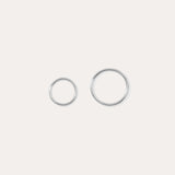 The 14K Solid White Gold 20G Mini Clicker, shown in two shiny sizes on a plain white background, is perfect for use as a clicker or nose ring.