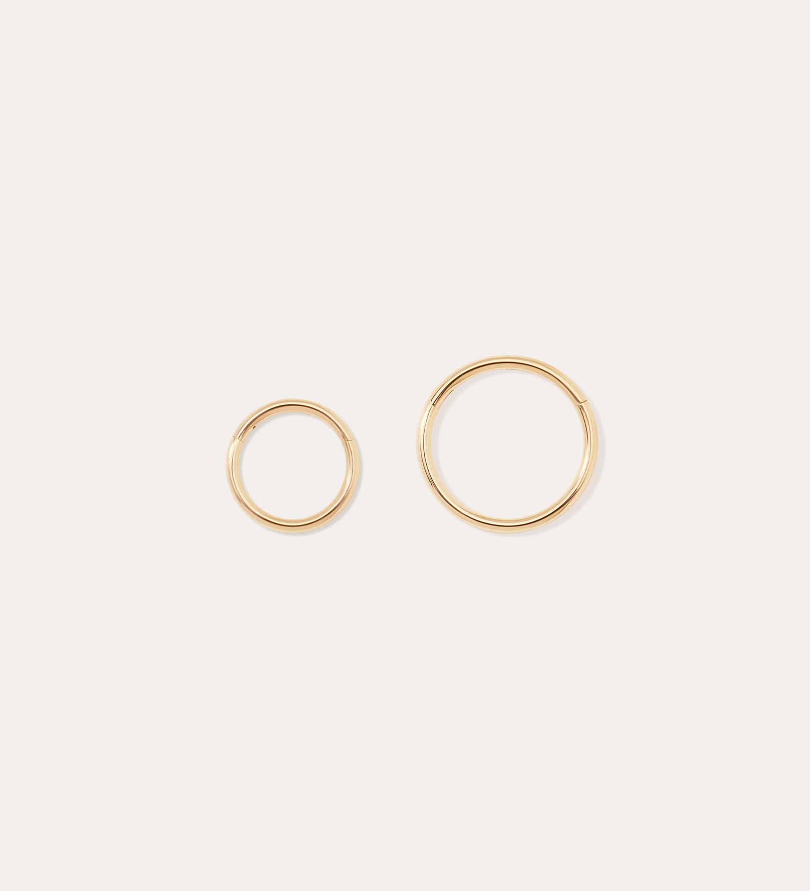 The 14K Solid Yellow Gold 20G Mini Clicker hoops, shown in two sizes on a plain white background, are perfect for classic cartilage wear or as minimalist hoop earrings.