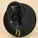 Black ear with gold earrings on a beige background with solid gold flatback studs
