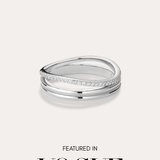 The Noor Pavé Triple Band Ring in Silver, featuring a modern curved design and a row of pavé diamonds, sits centered on a light background. Below the ring, black text reads FEATURED IN VOGUE.