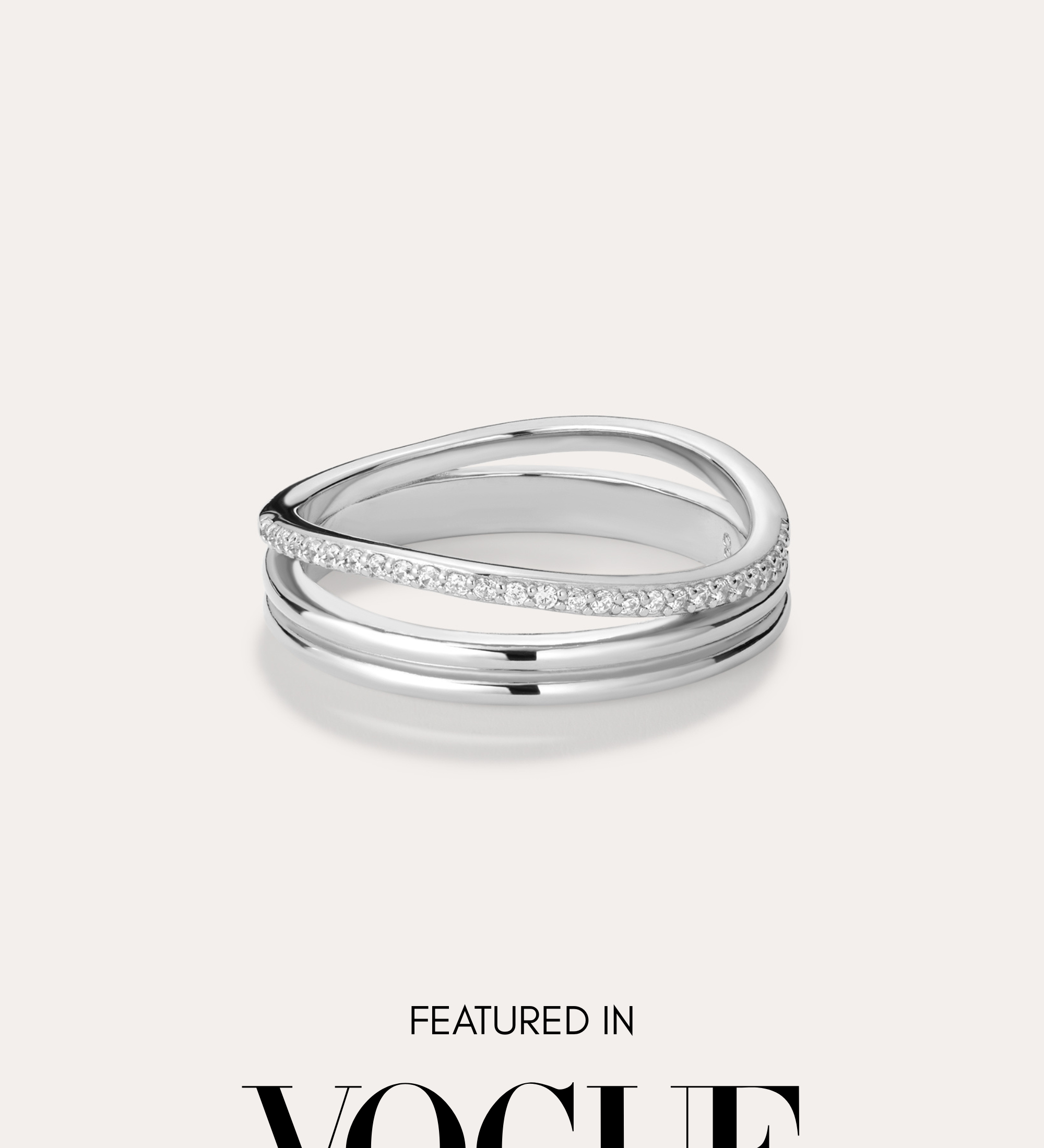 The Noor Pavé Triple Band Ring in Silver, featuring a modern curved design and a row of pavé diamonds, sits centered on a light background. Below the ring, black text reads FEATURED IN VOGUE.