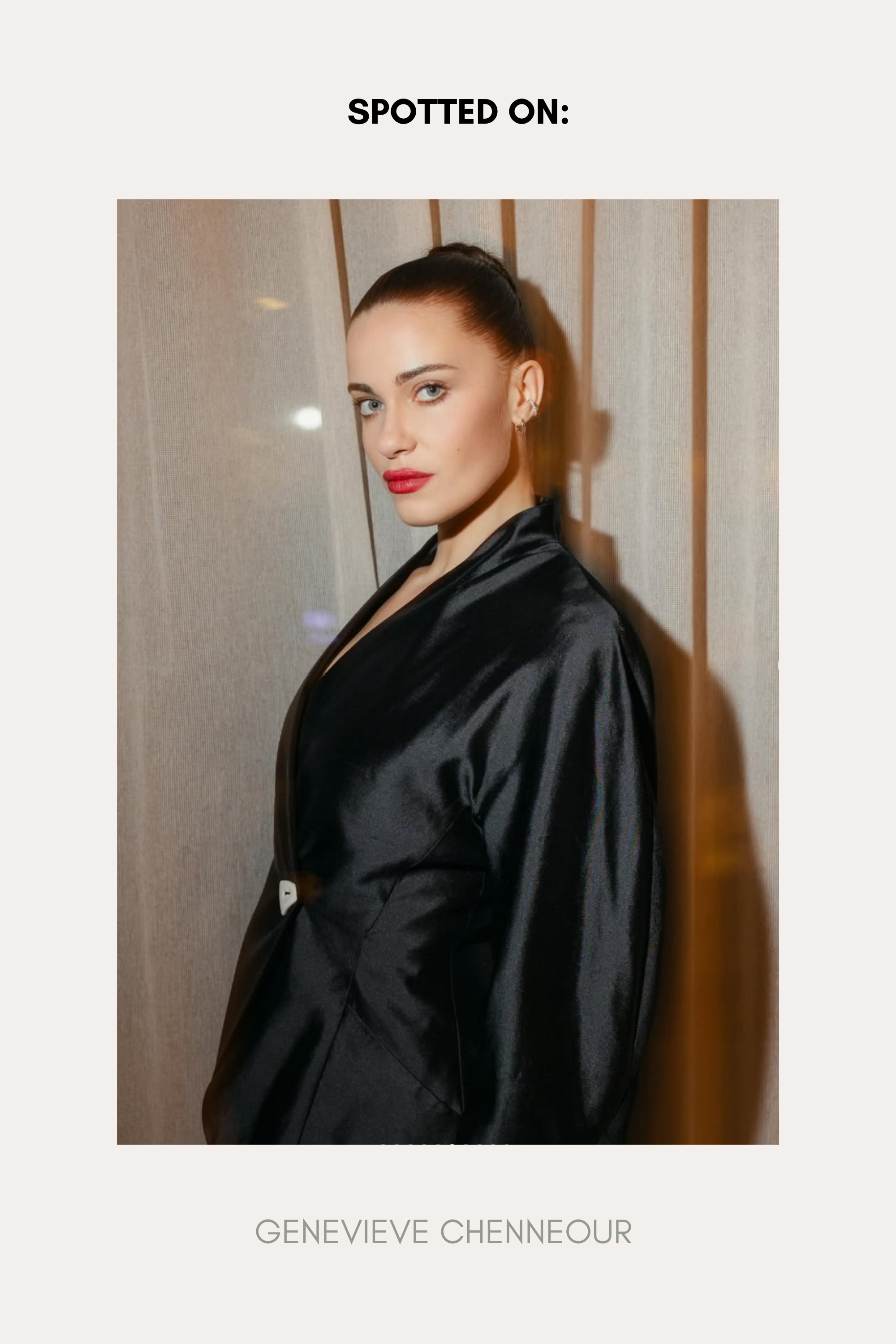 A woman with fair skin and dark hair in a sleek bun wears a shiny black jacket and the Vina Crystal Bezel Ear Cuff in Silver, standing before beige curtains. Text above reads “SPOTTED ON:” and below is the name “GENEVIEVE CHENNEOUR.”.