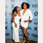 Two women smile in front of a Noughts + Crosses and BBC iPlayer backdrop. One wears a white dress; the other pairs her white suit with the Nola Pavé Triple Band Ring in Silver for added sparkle.