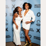 Two women smile in front of a Noughts + Crosses and BBC iPlayer backdrop. One wears a white dress; the other pairs her white suit with the Nola Pavé Triple Band Ring in Silver for added sparkle.
