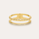 The Molten Crystal Double Band Ring in Gold features 18k gold plating, two connected bands—one with a twisted rope design and the other adorned with cubic zirconia—shown against a light background.