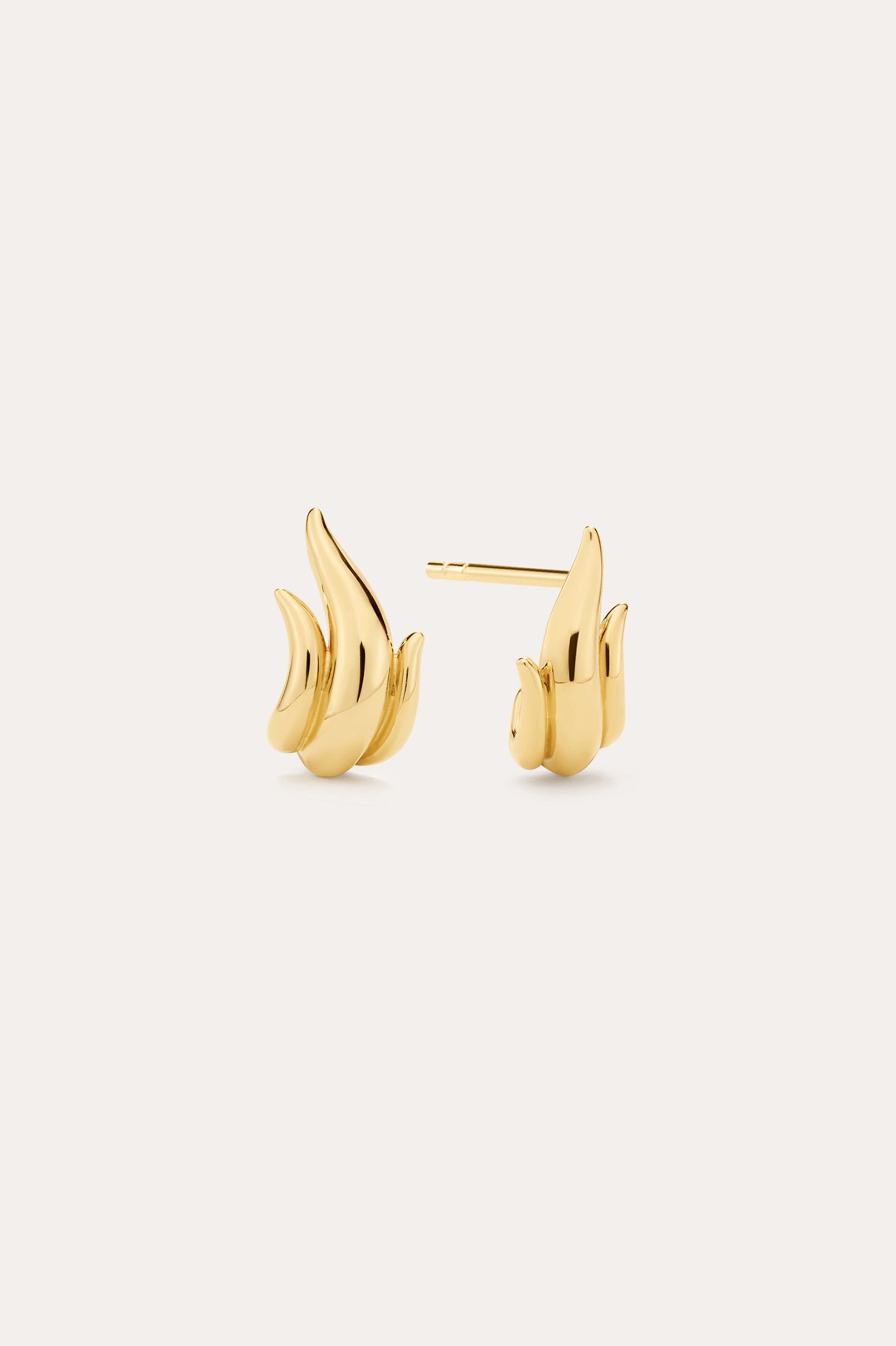 A pair of Flame Stud Earrings in Gold with a sculptural, flame-inspired design and 18k gold plated finish are shown on a light background—one facing forward and the other displaying the side and post.
